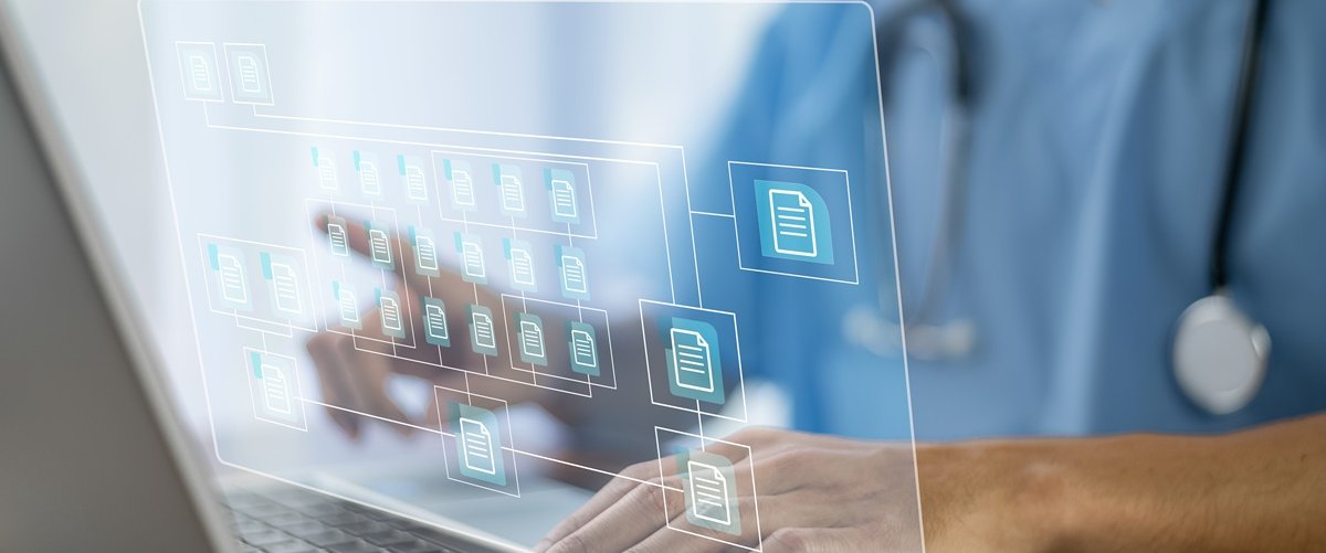 A doctor wearing blue scrubs uses a laptop. A graphic of computer folders to represent electronic patient record systems is superimposed on the photo.