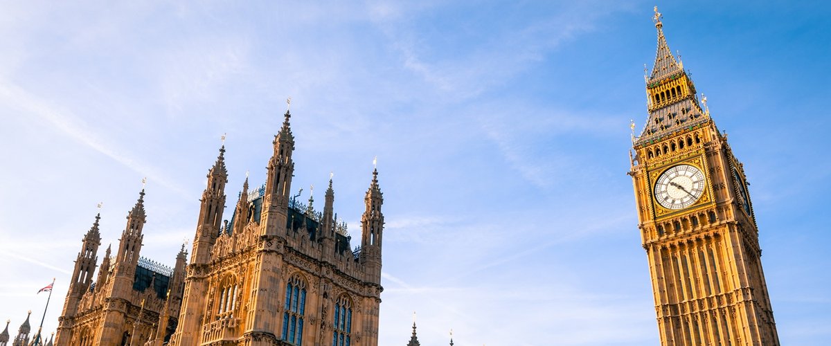Exterior view of the Houses of Parliament and Big Ben, against a bright blue sky.