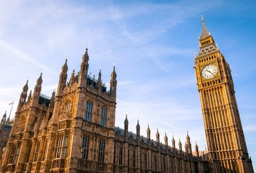 Exterior view of the Houses of Parliament and Big Ben, against a bright blue sky.