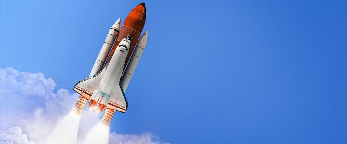 A space shuttle launches into a blue sky.