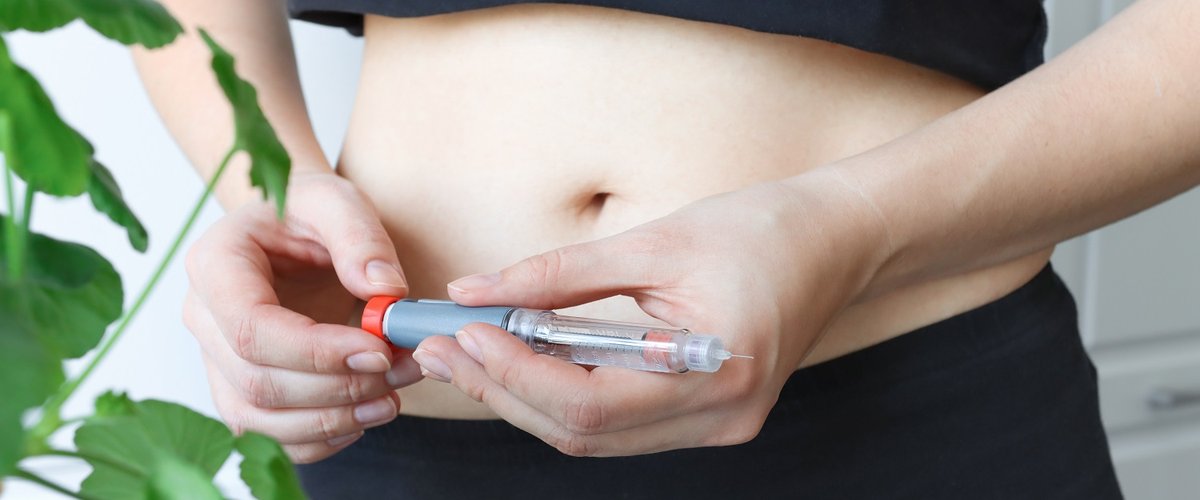 A young diabetic woman holds a syringe pen to inject insulin.