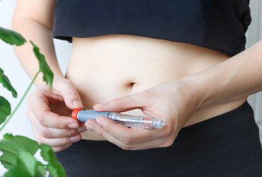 A young diabetic woman holds a syringe pen to inject insulin.