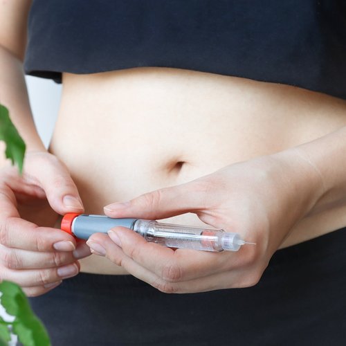 A young diabetic woman holds a syringe pen to inject insulin.