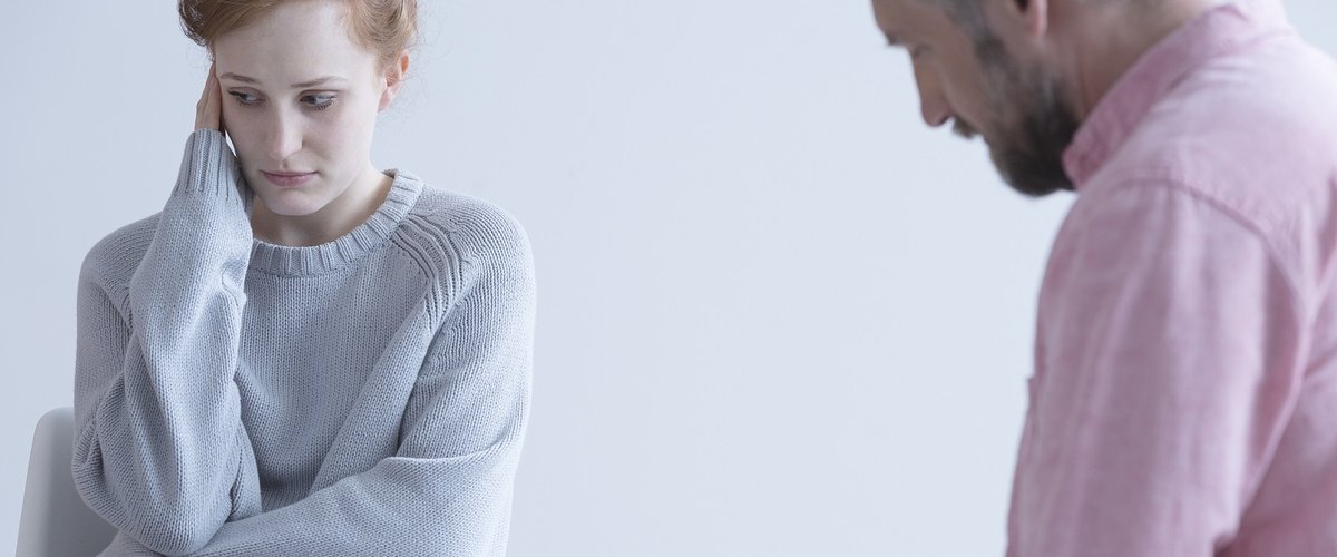 Young woman wearing a baggy long sleeve jumper meets with her doctor.