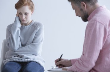 Young woman wearing a baggy long sleeve jumper meets with her doctor.