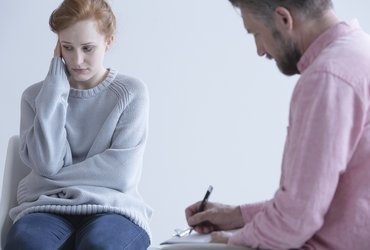 Young woman wearing a baggy long sleeve jumper meets with her doctor.