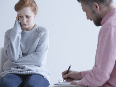 Young woman wearing a baggy long sleeve jumper meets with her doctor.