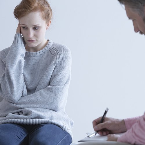 Young woman wearing a baggy long sleeve jumper meets with her doctor.